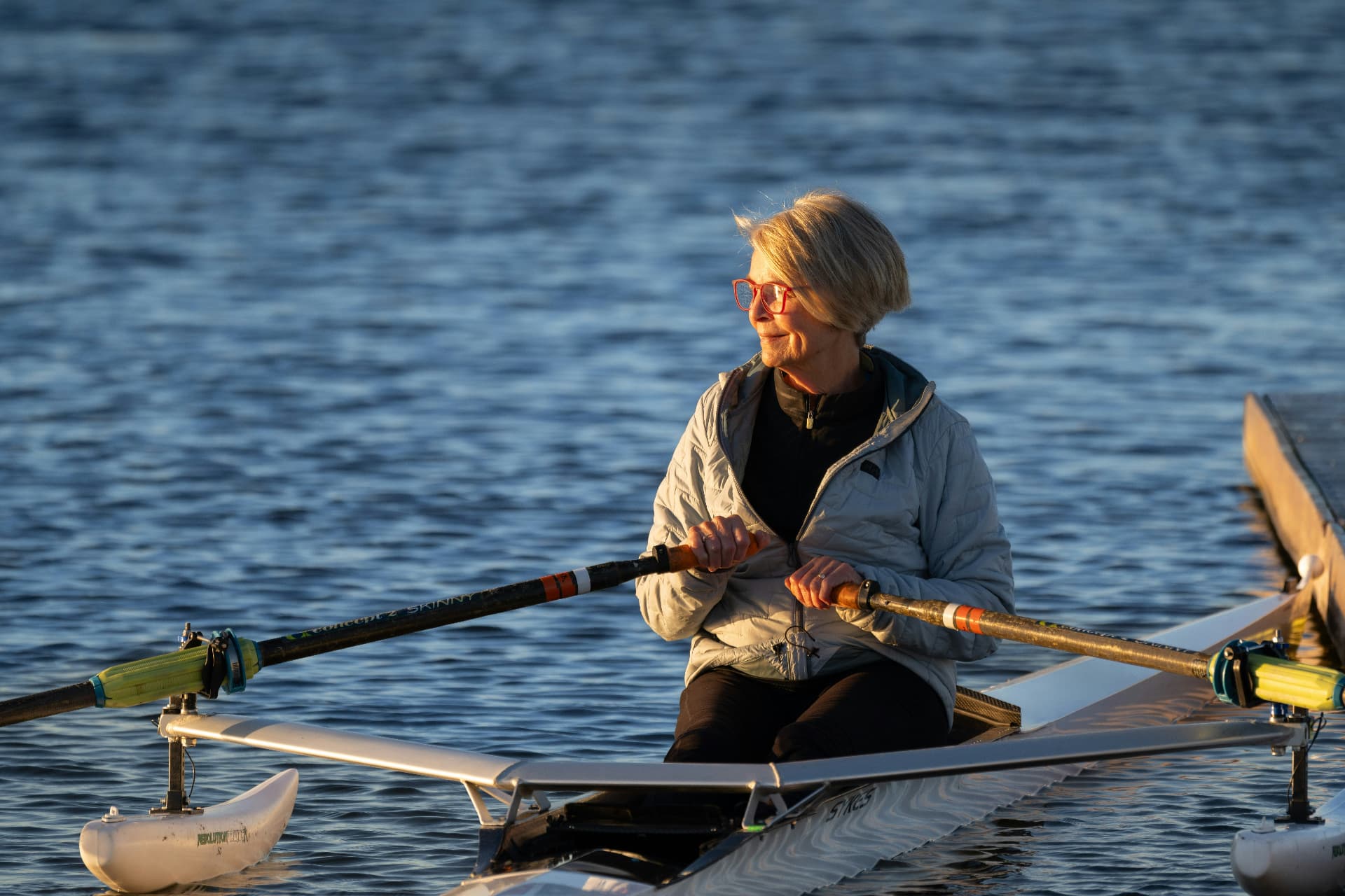 Eine ältere Frau rudert konzentriert auf einem See